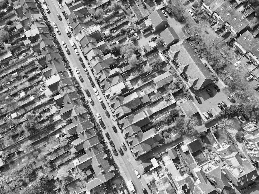 An aerial black-and-white photograph of a residential area along Kingston Road, showing rows of houses with pitched roofs and small individual gardens. The scene includes narrow streets with parked ca