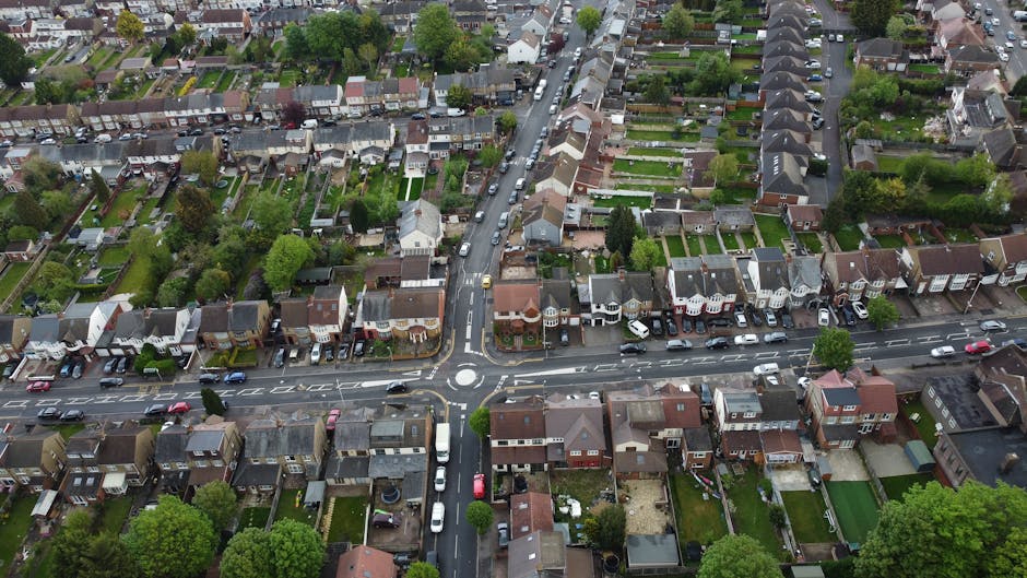 An aerial black-and-white photograph of a residential area along Kingston Road, showing rows of houses with pitched roofs and small individual gardens. The scene includes narrow streets with parked ca